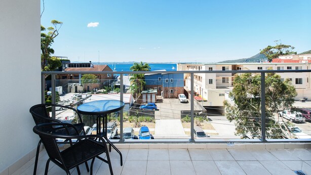 Un balcone con vista su una zona costiera, che include edifici e un cielo sereno.