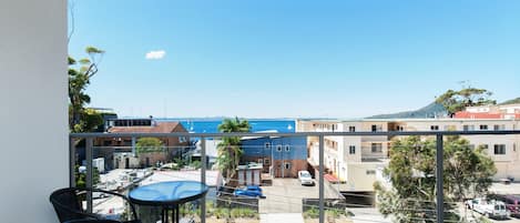 A balcony with a view of a coastal area, including buildings and a clear sky.