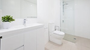 Un bagno moderno con lavandino bianco, un water e una cabina doccia in vetro.