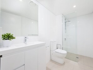 Een moderne badkamer met een wit wastafelmeubel, toilet en een douchecabine met glazen wanden.