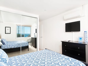 Een slaapkamer met een bed, een dressoir, een televisie en een raam met uitzicht.
