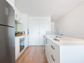 A modern kitchen with a refrigerator, oven, and sink.