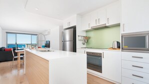 A modern kitchen with white cabinetry, stainless steel appliances, and a large island. - A modern, Coastal Unit in Shoal Bay! (Shoal Bay)