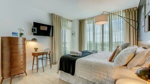 A hotel room with a bed, a desk, a chair, a TV, and a window with curtains. - Corner Deluxe Studio w/ City View Free Park & Pool (Miami)