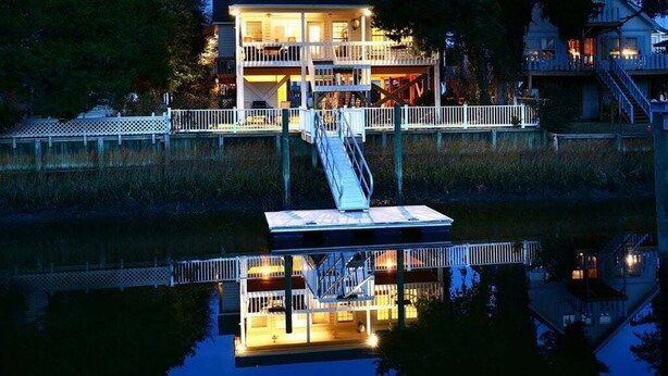 A waterfront property with a dock, a multi-level building, and a reflection in the water. - Charming oceanfront retreat, Sea Shanty / 153 Marlin, with 3 beds in Holden Beach. (Holden Beach)