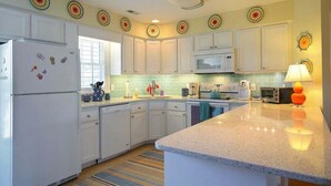 A modern kitchen with white cabinets, a microwave, a refrigerator, and a granite countertop. - Charming oceanfront retreat, Sea Shanty / 153 Marlin, with 3 beds in Holden Beach. (Holden Beach)