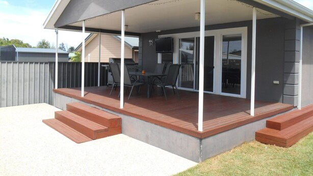 Un patio cubierto con una parrilla, asientos al aire libre y un televisor.