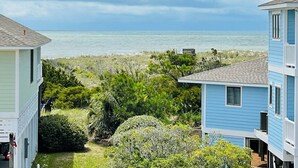 A coastal residential area with houses overlooking the ocean, dense vegetation, and a clear sky.