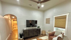 A modern living room with a flat-screen TV, dark wood cabinet, leather sofa, and a unique wooden coffee table.