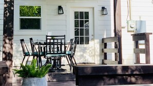 A covered patio with a table and chairs, a potted plant, and a wooden bench.