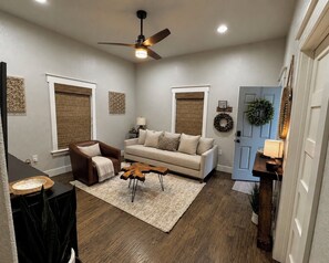 A living room with a brown leather chair, a beige sofa, a wooden coffee table, and a ceiling fan. - North FW Stockyards Getaway (Fort Worth)
