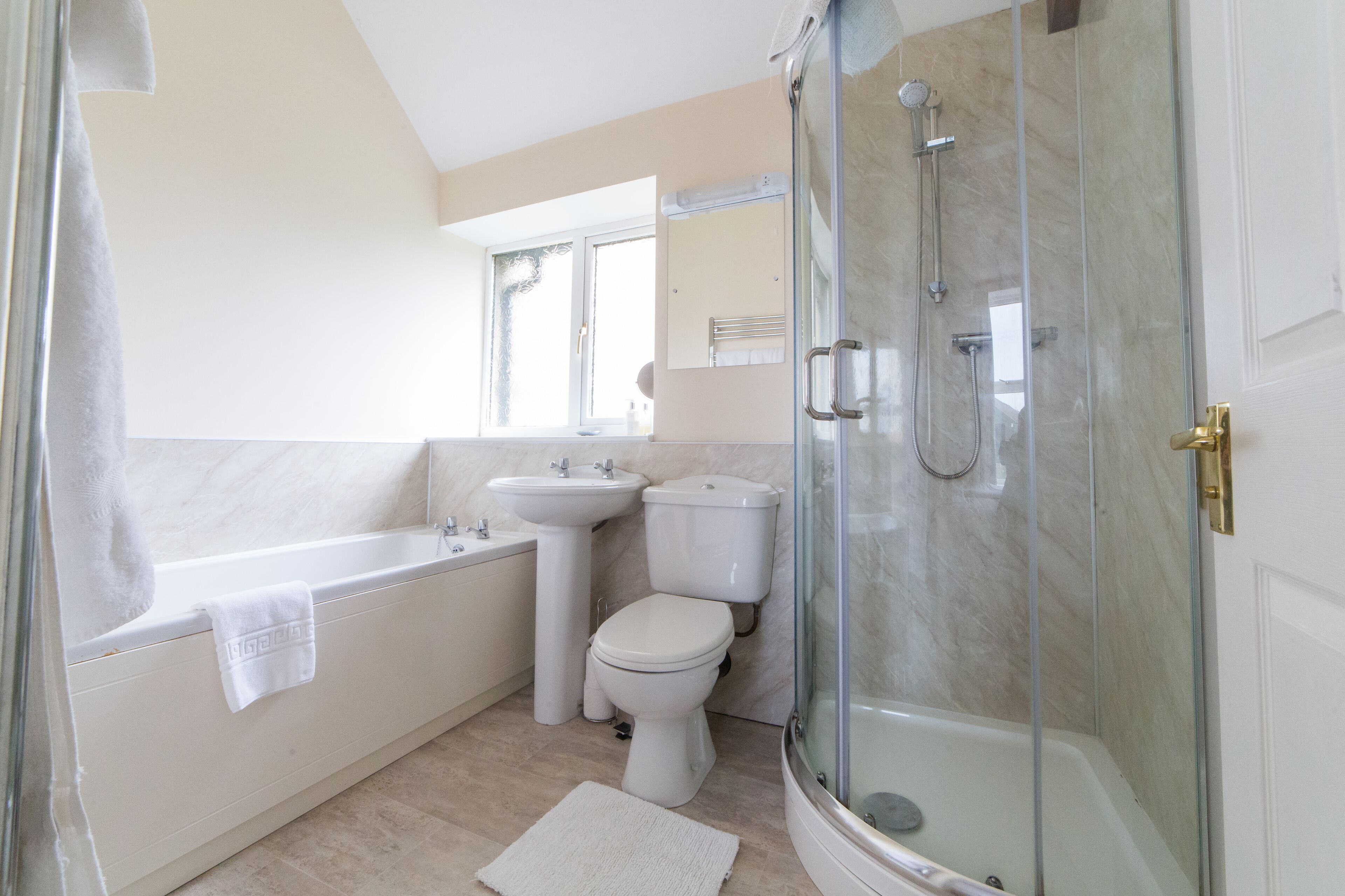 A modern bathroom with a glass-enclosed shower, a bathtub, a sink, and a toilet.