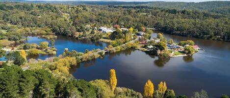 A lakeside property with a small dock, surrounded by dense forest and hills.