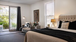 Une chambre d’hôtel avec un grand lit, un canapé, un bureau avec une lampe et un tableau au mur.