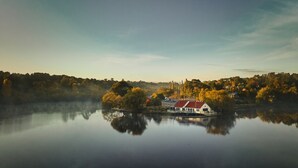 Un lac paisible avec une maison sur une petite île, entouré d’arbres et sous un ciel dégagé.