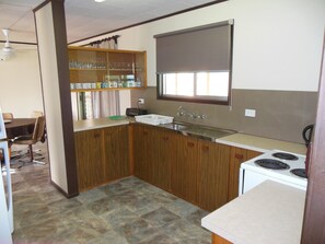 A compact kitchen with a sink, stove, and wooden cabinets.