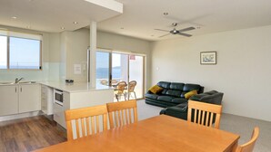 A modern kitchen with a dining area, a sofa, and a view of the sea. - Del Rae, Unit 12/25 Shoal Bay Road - North-facing apartment overlooking the Bay (Shoal Bay)