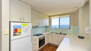 A modern kitchen with a refrigerator, stove, oven, and sink. There is a window with a view of the sea. - Del Rae, Unit 12/25 Shoal Bay Road - North-facing apartment overlooking the Bay (Shoal Bay)