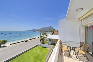 A balcony with a view of the sea, a table, and two chairs.