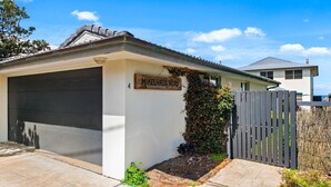 Uma casa térrea com garagem, uma placa de madeira com a inscrição 'Mikelhaus Nord', e um quintal cercado.
