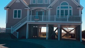 Een tweelaags huis met een balkon, een garage, en een bord dat het te koop aangeeft.