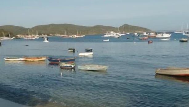 Una playa con barcos y cielo despejado.
