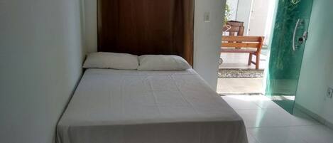 A bedroom with a bed, a wooden headboard, a bench outside, and a green door.