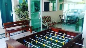 Una habitación con mesa de futbolín, un banco y un sofá.