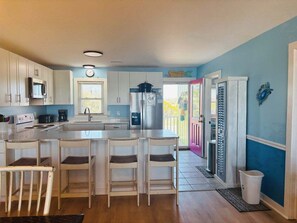 A kitchen with a central island, white cabinets, a microwave, and a refrigerator.