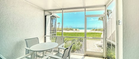 A balcony with a table and chairs, a view of the beach, and a 'NO PARKING' sign.