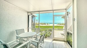Un balcon avec une table et des chaises, une vue sur la plage et un panneau indiquant « INTERDICTION DE STATIONNER ».