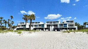 A beachfront hotel with multiple balconies and a sandy beach in the foreground.