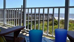 Une terrasse en bois offrant une vue sur la plage et l’océan.