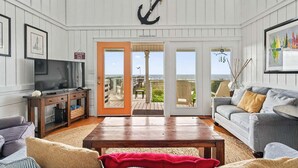 Ein Zimmer mit Fernseher, Holzmöbeln, einem großen Fenster und Meerblick.