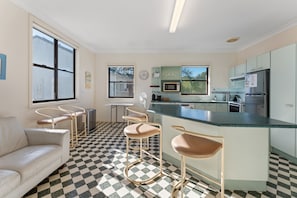 A modern kitchen with a checkered floor, a bar area with stools, a refrigerator, and a microwave.