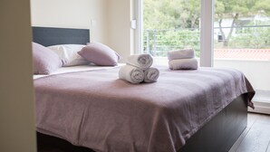 A neatly made bed with a headboard, pillows, and rolled towels on a balcony with a view of trees. - Villa Lele - Pool, Sea & Mountain View (Novigrad)