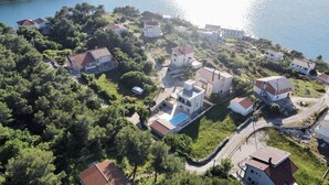 An aerial view of a coastal residential area with houses surrounded by greenery and a body of water. - Villa Lele - Pool, Sea & Mountain View (Novigrad)