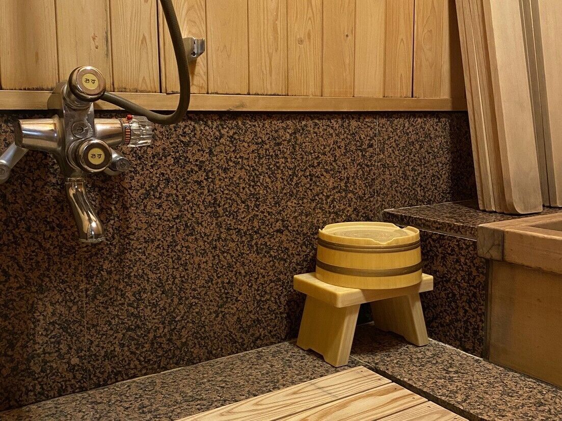 A bathroom with a granite countertop, a wooden stool, and a faucet.