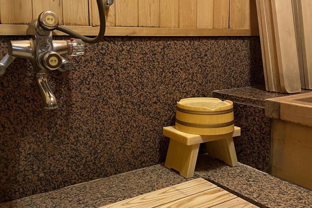 A bathroom with a granite countertop, a wooden stool, and a faucet.