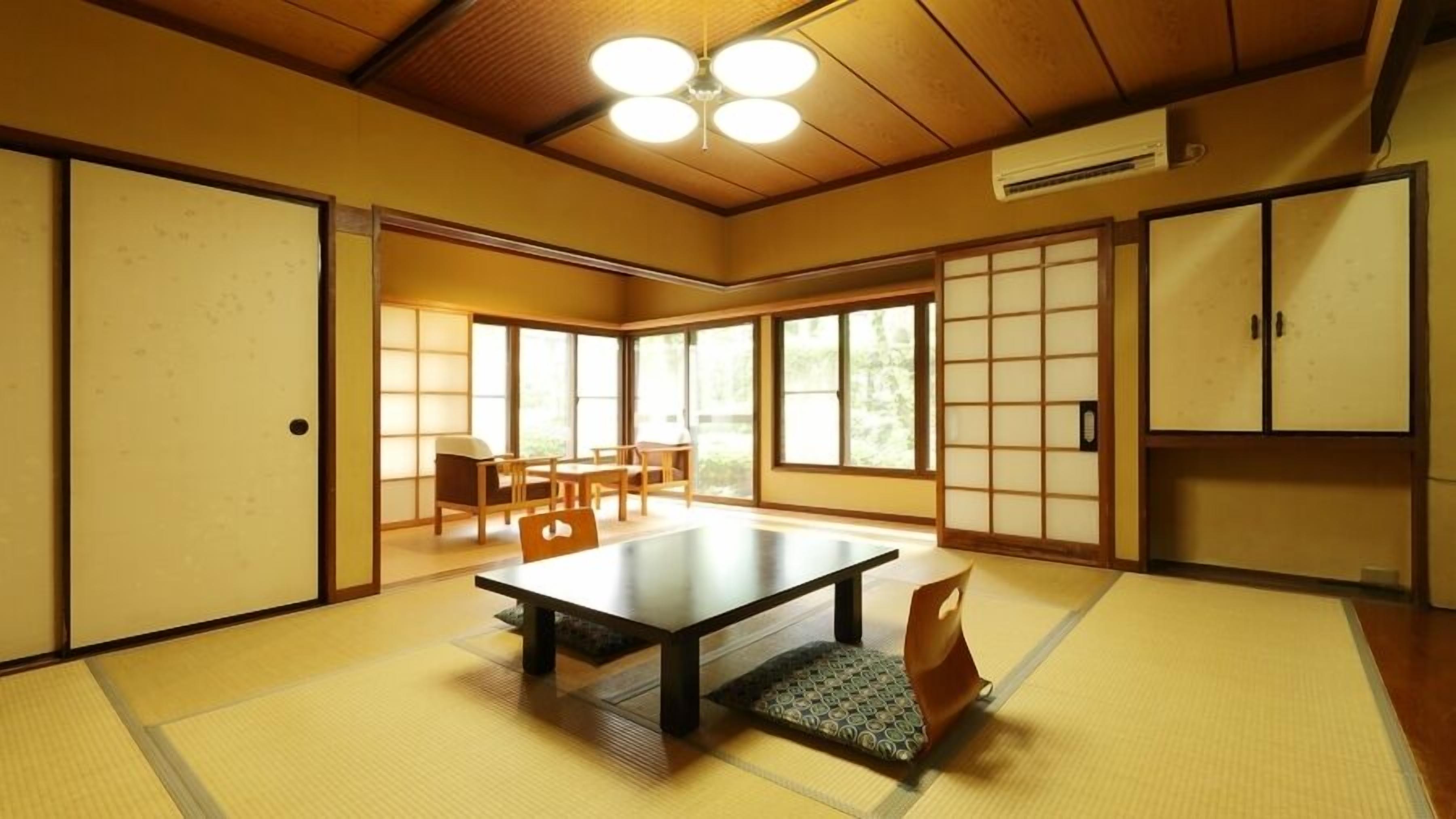 A traditional Japanese room with tatami flooring, a low table, sliding doors, and a view of the outdoors.