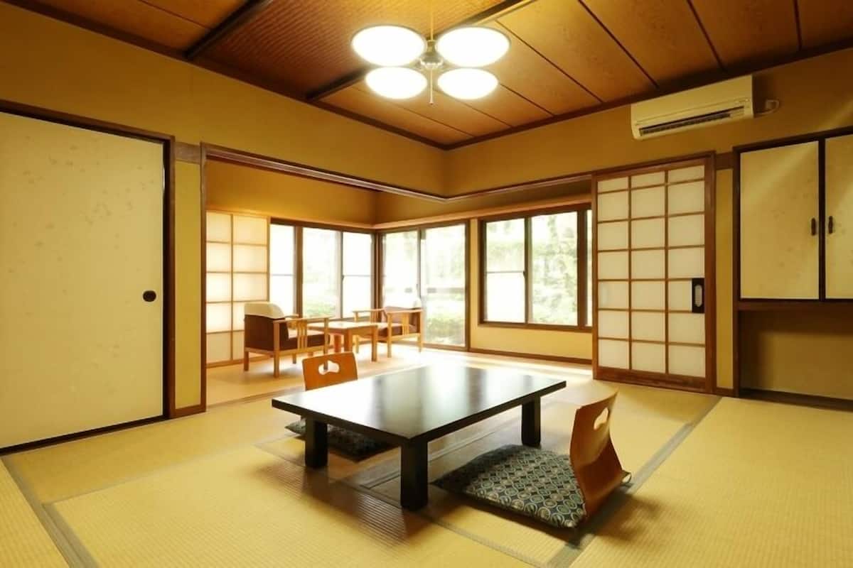 A traditional Japanese room with tatami flooring, a low table, sliding doors, and a view of the outdoors.