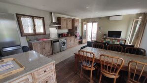 A spacious kitchen with wooden cabinets, a built-in dishwasher, and a dining area with a large table and chairs. - Wonderful house at the heart of Provence 1km to beach with terrace and parking (Fos-Sur-Mer)