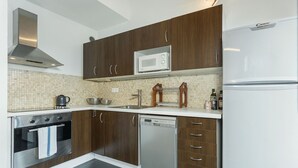 Een moderne keuken met houten kastjes, een oven van roestvrij staal, een vaatwasser, een magnetron en een koelkast.
