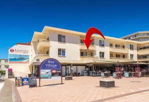A hotel with a sign for Bay Village, featuring a large arrow pointing to it.