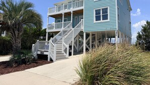 A multi-story beachfront house with a balcony, a staircase, and a number 866 sign.