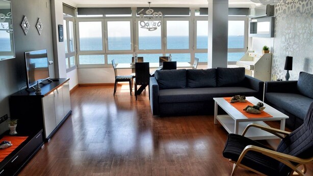 Ein modernes Wohnzimmer mit Sofa, Couchtisch und Essbereich mit Meerblick.