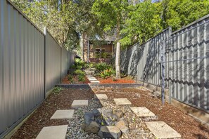 A narrow pathway flanked by metal fences leading to a building with a brick facade. - Nelson Bay Ocean Jewel (Nelson Bay)