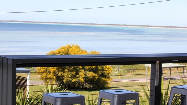 Ein Balkon mit Blick auf ein ruhiges Meer und eine entfernte Küste.