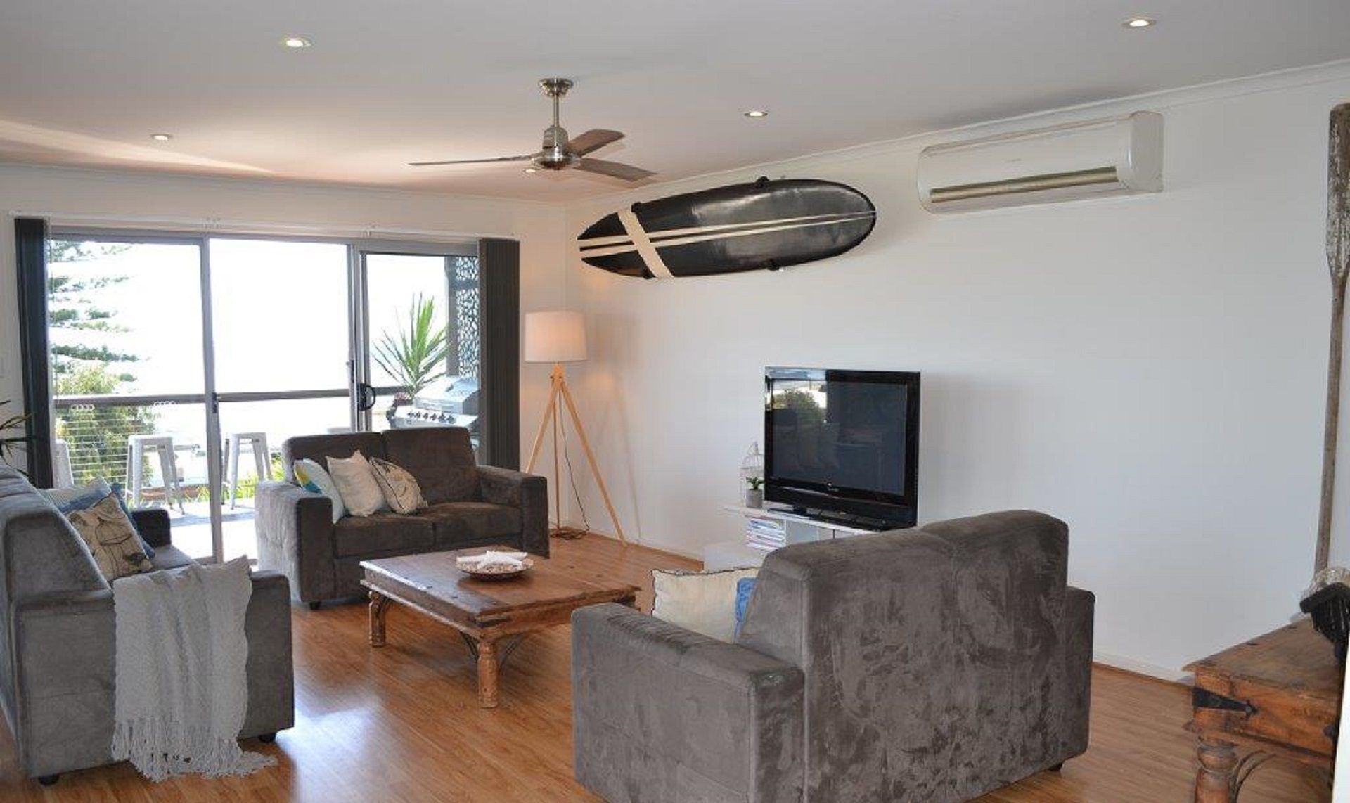 A living room with a sofa, armchairs, a coffee table, a TV, and a ceiling fan.
