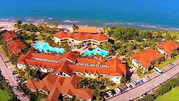 A resort with multiple buildings, a swimming pool, and a beach.